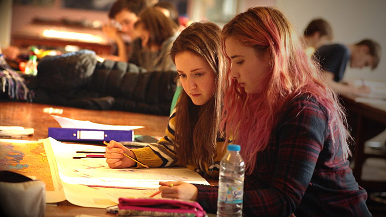 Two female students working at a classroom table