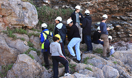 Students in hard hats examining a cliff face